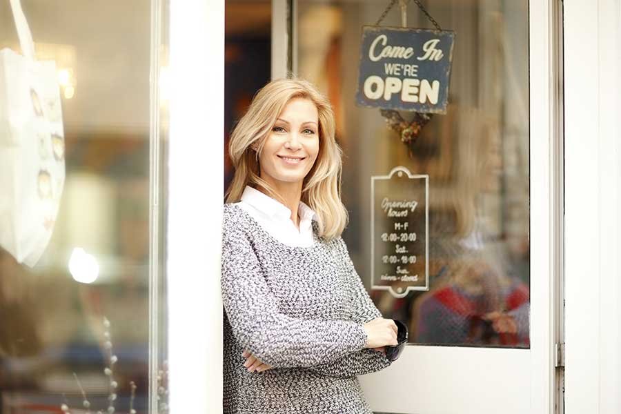 A friendly woman standing in the doorway of her local business.